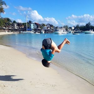 Teenage girl backflipping at beach 