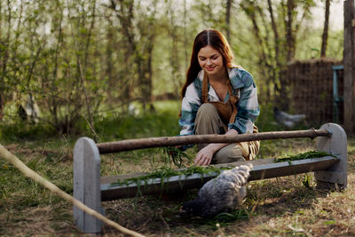 Smiling woman feeding chickens in farm