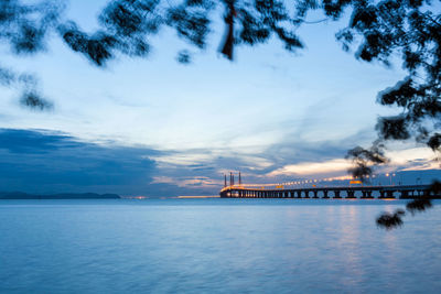 View of bridge over sea against cloudy sky