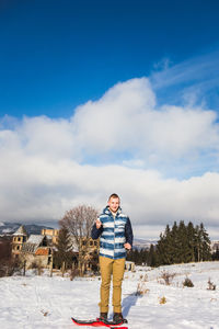 Portrait of man standing on snow covered land against sky