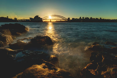 Bridge over sea against sky during sunset