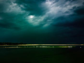 Scenic view of illuminated field against cloudy sky at night