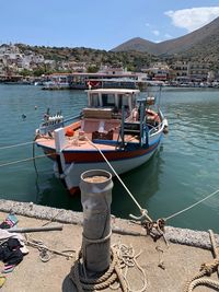 Fishing boat moored at harbor against sky