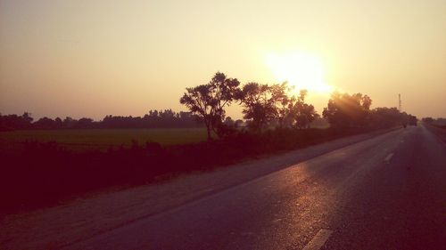 Road amidst trees against sky during sunset