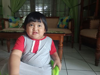 Portrait of cute girl sitting on chair at home