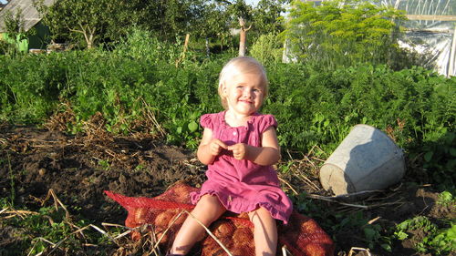 Girl sitting on sack against plants