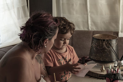 Mother and 3-year-old caucasian son make crafts in caravan while on vacation