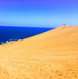 Scenic view of beach against clear blue sky