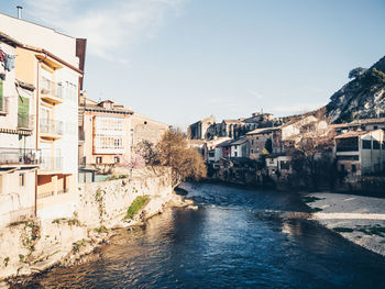 Buildings by river against sky in city