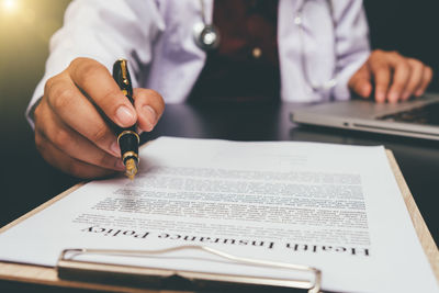 Midsection of man reading book on table