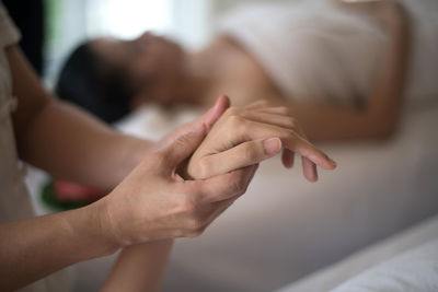 Midsection of therapist massaging young woman hand in spa