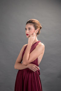 Portrait of young woman standing against white background