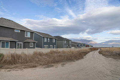 Houses on field by road against sky