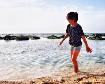 Full length of girl on beach against sky