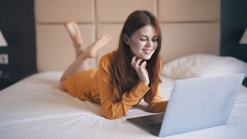 Portrait of young woman using laptop on bed at home