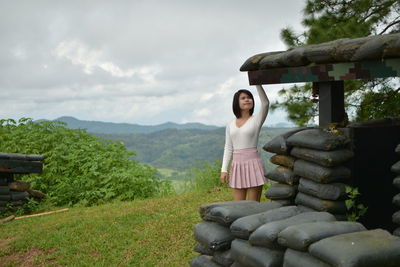 Young woman standing by sack against sky