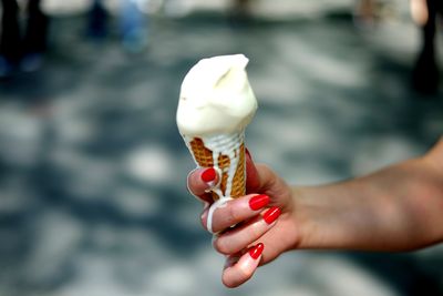 Cropped image of woman holding meting ice cream cone outdoors