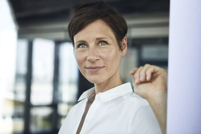 Portrait of smiling businesswoman in office looking out of window