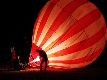 People preparing hot air balloons at night