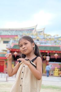 Smiling girl gesturing while standing outdoors