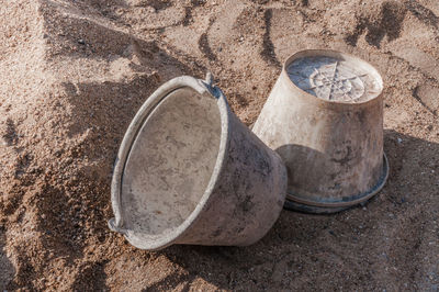 Plastic bucket with cement placed on on the sand at construction site