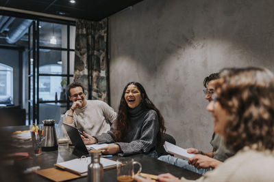 Cheerful multiracial colleagues discussing at conference table in board room