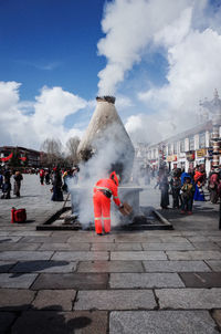 People on street against cloudy sky