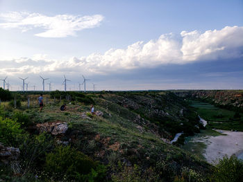 Scenic view of land and wind turbines against sky