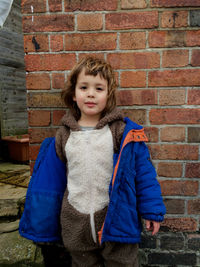 Portrait of cute girl in costume standing against brick wall