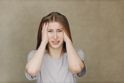 Portrait of young woman standing against wall