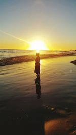 Silhouette man standing on beach against sky during sunset