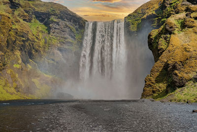 Beautiful view of skogafoss waterfall against cloudy sky during sunset
