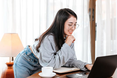 Smiling young woman looking at laptop in office