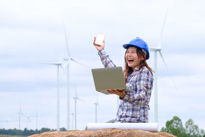 Young woman using smart phone against sky