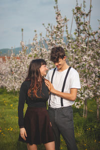 Love between two young people walking under apple trees. candid portrait of couple in casual clothes