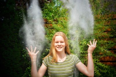 Smiling teenage girl throwing powder against plants