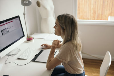 High angle view of female graphic designer using computer at desk in house
