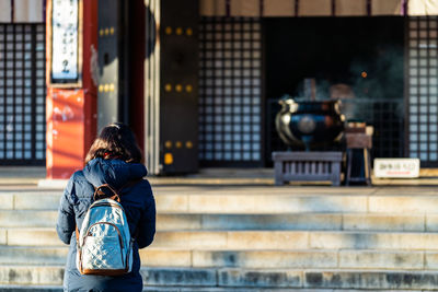 Rear view of man photographing woman in city