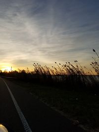 Road by silhouette landscape against sky during sunset