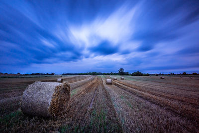 Hay bales on field against sky