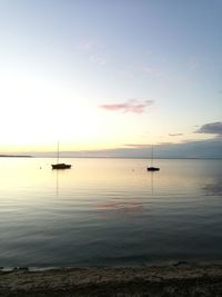 Boats in sea at sunset