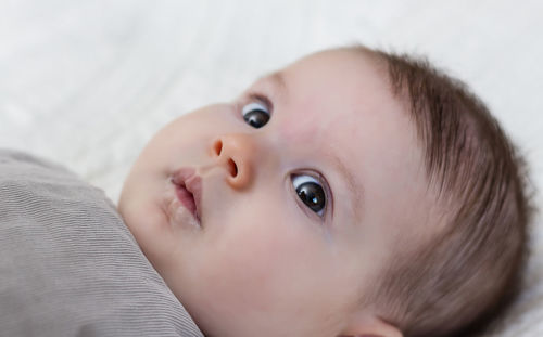 Portrait of cute baby girl lying on bed