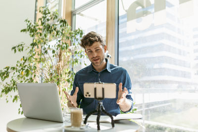 Young businessman discussing during meeting on video call at table in cafe