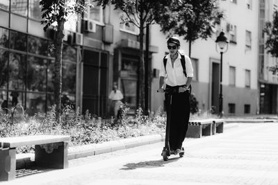 Businesswoman with backpack riding a scooter to work down the street in the city.