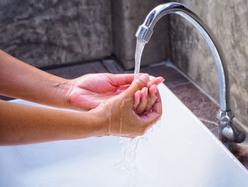 Cropped hand of woman washing hands in bathroom