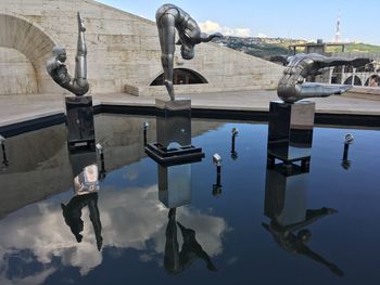 Reflection of man sculpture on building against sky