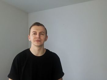 Portrait of young man standing against wall