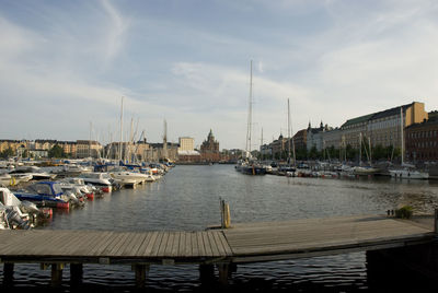 Boats moored at harbor against sky in city