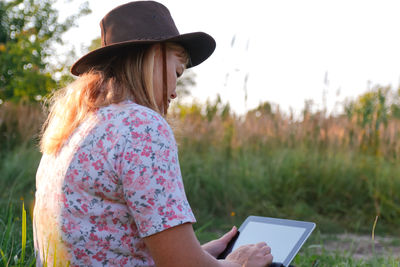 Young woman using laptop while sitting on field