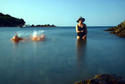 Senior woman in sea against clear blue sky